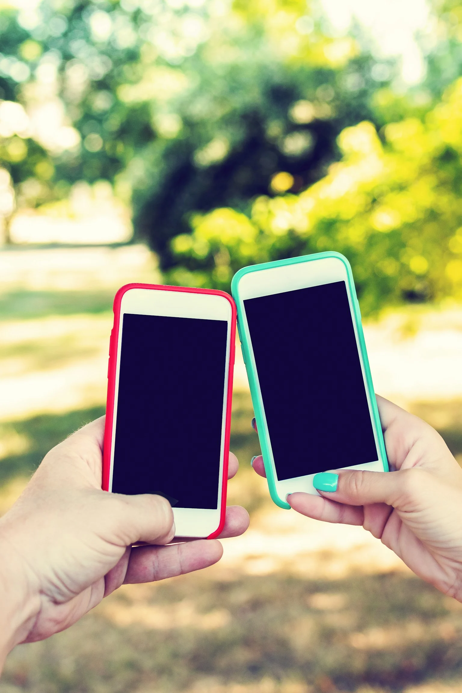 Twee telefoons naast elkaar, vastgehouden in handen.