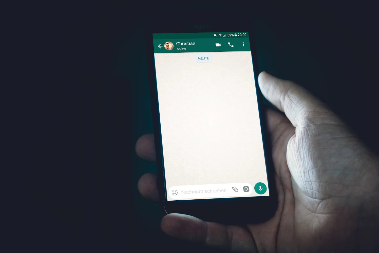 Een hand houdt een telefoon met een berichtenapp vast.