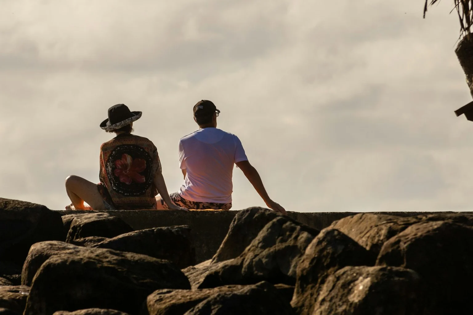 Twee volwassenen zitten naast elkaar op rotsen aan zee.